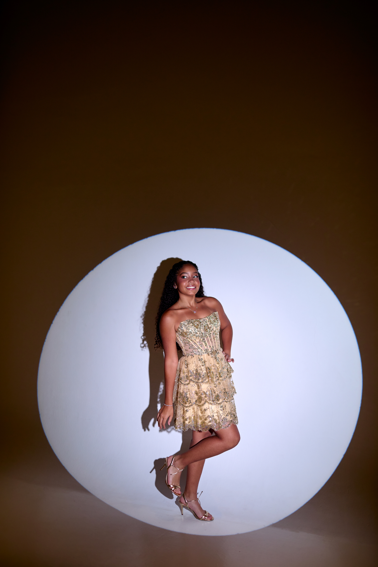 Debutante em vestido dourado diante de um círculo de luz